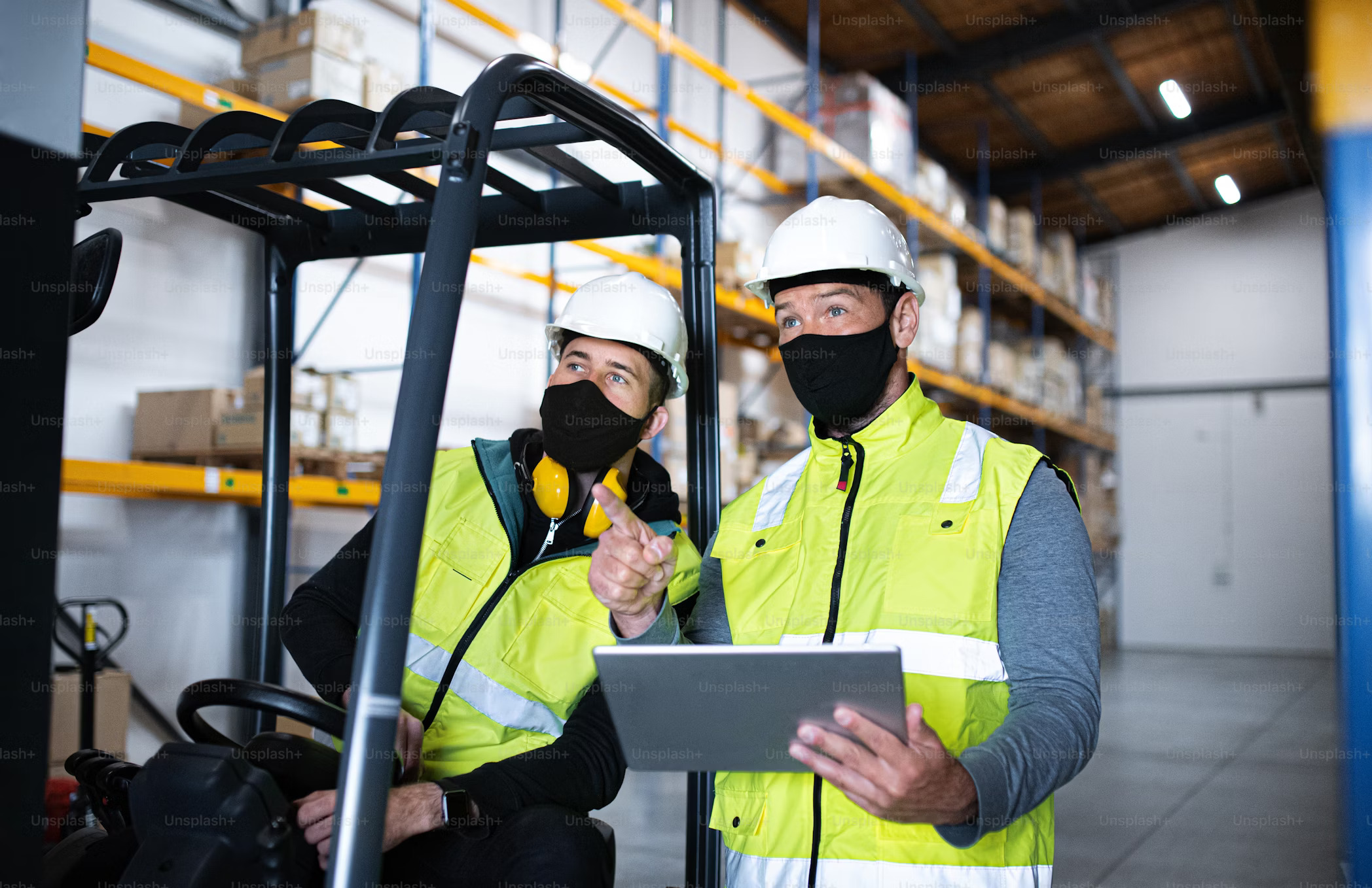 Factory floor with engineer reviewing ERP tasks on a tablet